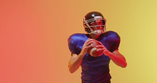 Athlete wearing football gear and holding ball, illuminated with neon lights. Suitable for usage in sports promotion, advertisements, competition highlights, visual arts, and fitness campaigns.