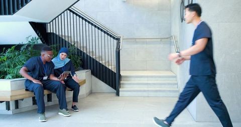 Healthcare professionals reviewing tablet in modern hospital corridor, teamwork