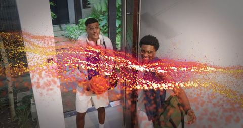 Young athletes entering through glass door holding basketball with golden particle trail