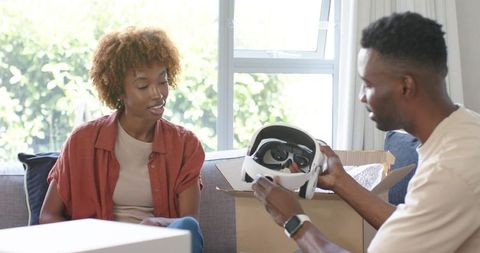 Couple unboxing white vr headset in living room sharing excitement and tech discovery
