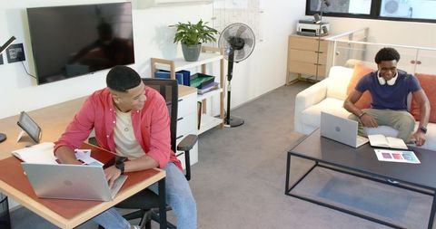 Young diverse coworkers collaborating in modern lounge workspace with laptops and notes