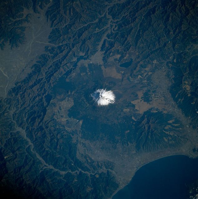 This stunning image of Mount Fuji, Japan, was captured by the Space Shuttle Columbia during its mission in 1983. The snowy peak of this iconic and active stratovolcano is clearly visible against the backdrop of its surrounding rugged terrain and the nearby coastline. Such images are perfect for illustrating articles about space missions, geographic studies, natural landmarks, and travel destinations. They are also suitable for educational purposes and environmental awareness campaigns.