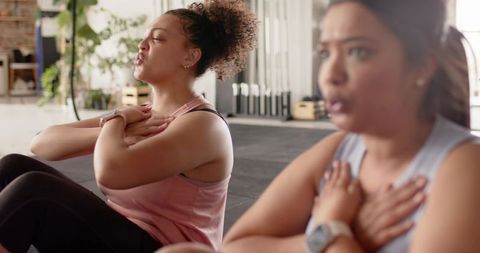 Multicultural women practicing breath-focused core workout in sunlit fitness studio