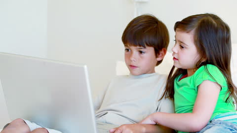 Curious Siblings Using Laptop in Bright Room
