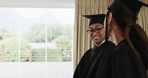 Graduates smiling wearing caps and gowns indoors