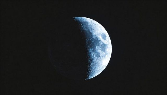 Glowing Half Moon Highlighting Cratered Lunar Surface Along Sharp Terminator Line