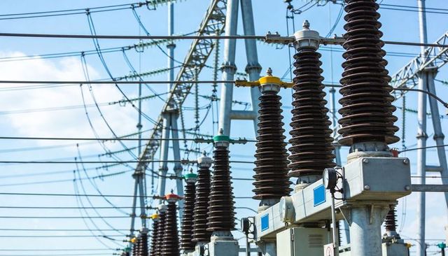 High-voltage substation insulators and switchgear standing under blue sky with colored caps