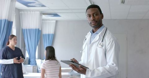 Confident Male Doctor With Tablet Collaborating in Hospital Ward