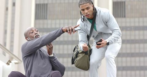 Trainer Coaching Trainee on Urban Steps Pointing at Phone During Outdoor Workout