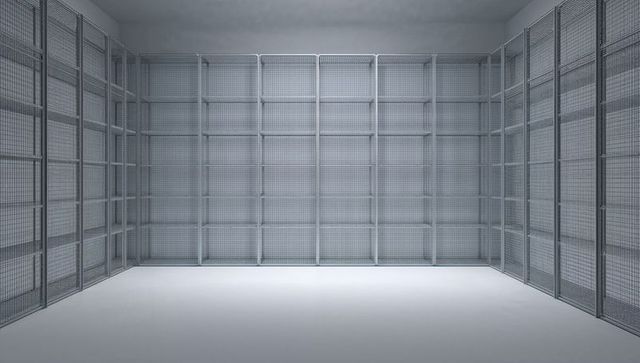 Empty wire mesh storage cages in minimalist industrial warehouse with steel shelving