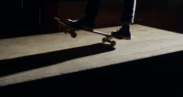 Low-light shot of a skateboarder performing a trick. The shadow and silhouette create a dramatic effect, perfect for skateboarding promotions, extreme sports events, and action-themed projects. This image could be used in lifestyle blogs, social media campaigns, or print materials to highlight urban culture and adventurous activities.