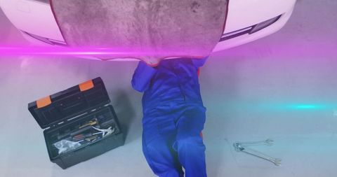 Mechanic inspecting car undercarriage in auto repair shop