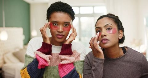 Diverse women relaxing with pink under-eye patches in softly lit room