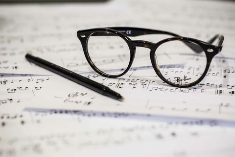 Eyeglasses resting on sheet music with pen