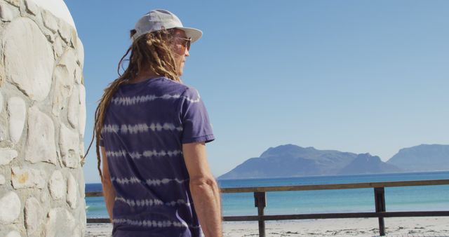 Man with dreadlocks enjoying sunny beach view with mountains - Download Free Stock Images Pikwizard.com