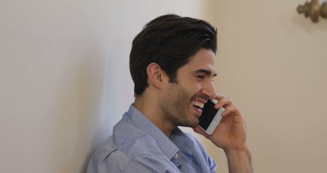 Man is smiling while talking on the phone. Ideal for illustrating concepts of casual communication, happiness, professional interactions, customer service, or everyday conversations.