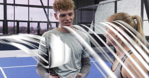 Indoor padel court training: young athletes talking with smartphone and motion light trails
