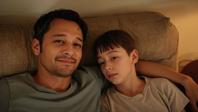 Father and Son Relaxing and Cuddling on Sofa Sharing Quiet Evening Together