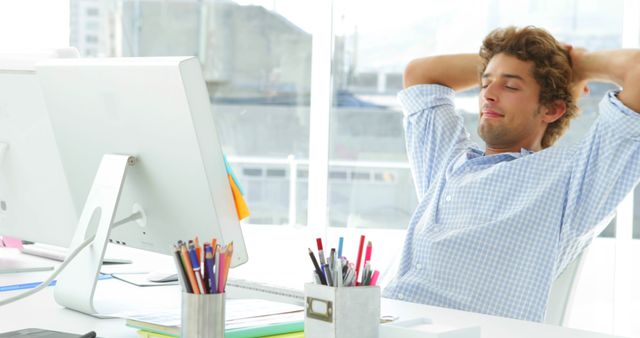 Relaxed Young Professional Taking Break at Desk in Modern Office - Download Free Stock Images Pikwizard.com