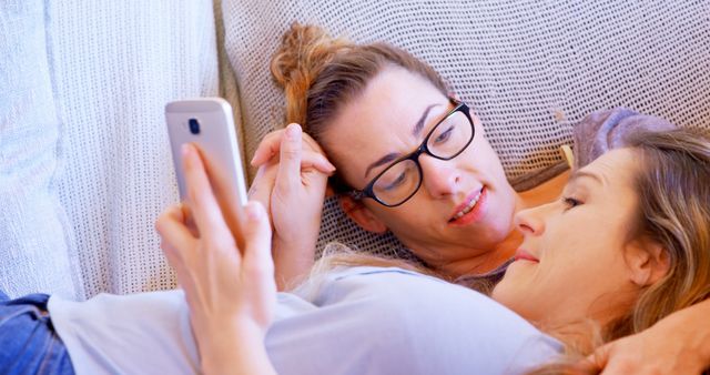 Two Women Relaxing Together on Couch Using Smartphone - Download Free Stock Images Pikwizard.com