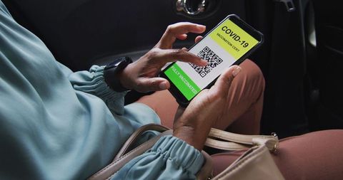 Businesswoman displaying covid-19 vaccination certificate on smartphone