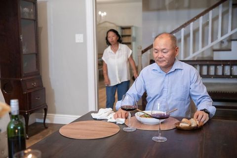 Senior chinese couple sharing quiet dinner at home man sitting woman approaching table
