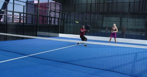 Diverse Teammates Playing Padel on Blue Court with Intensity
