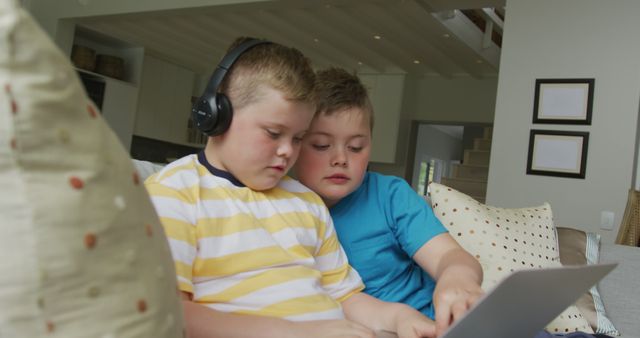 Caucasian boy with his brother sitting in living room and using laptop. family spending time at home.
