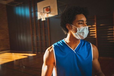 Basketball Player in Gym Wearing Mask Exhibiting Determination and Focus