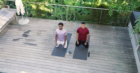 Diverse men meditating outdoors surrounded by nature