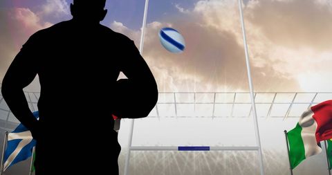 Silhouette of Rugby Player in Stadium with Flags and Ball