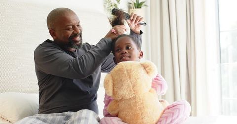 Father Gently Brushes Daughter's Hair in Cozy Bedroom