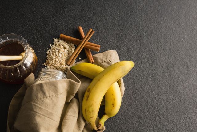 Close-up of honey, banana, oatmeal, cinnamon sticks on black background