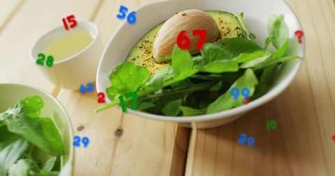 Fresh avocado and arugula salad featuring colorful numeric overlays on rustic wooden table