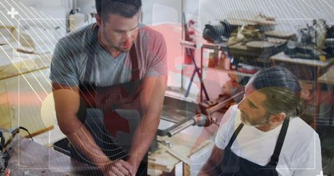 Apprentice learning from experienced mentor in carpentry workshop
