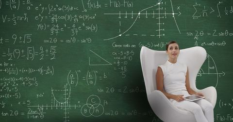 Smiling woman using tablet with mathematical formula chalkboard