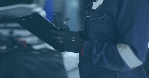Female mechanic inspecting engine and writing checklist on clipboard in garage workshop
