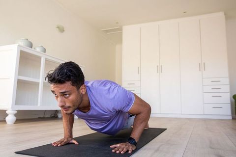 Focused Asian Man Doing Push-Ups on Home Gym Mat