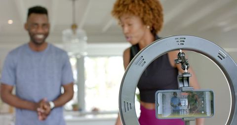 Filming fitness livestream with african american couple using ring light and smartphone