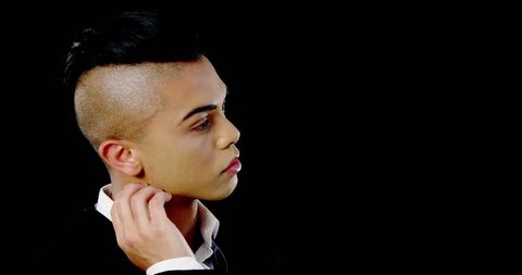 Young Man in Black Suit with Stylish Haircut on Dark Background