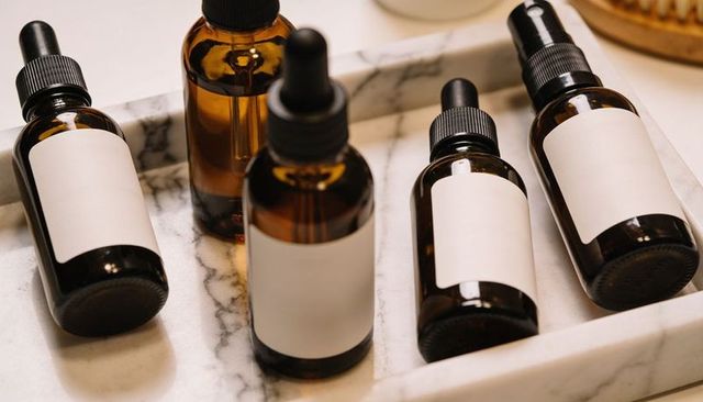 Amber dropper bottles with blank labels on marble tray for skincare branding mockups