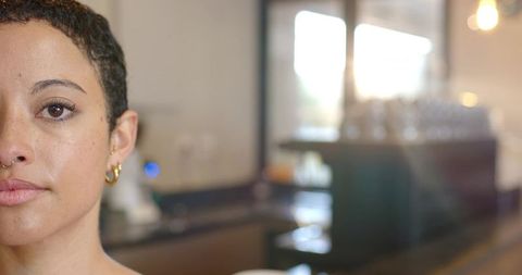African american adult woman with septum ring closeup looking at cafe counter, warm bokeh