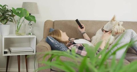 Woman Relaxing on Sofa with Fluffy Dog in Cozy Living Room