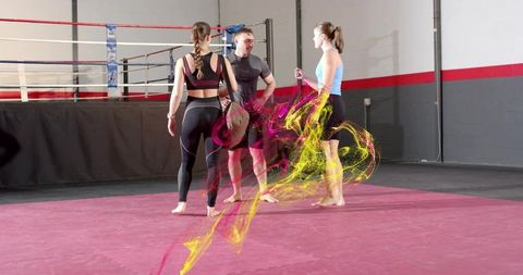 Coach training two female athletes on boxing mat with dynamic magenta smoke effect