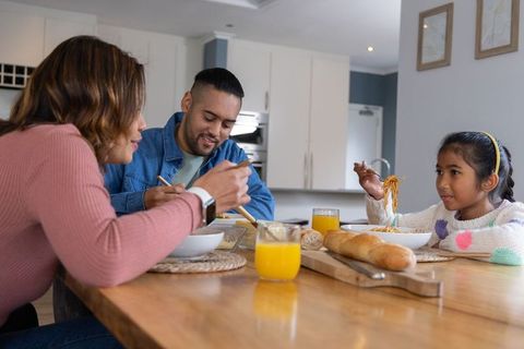 Young family enjoying homemade noodles at modern kitchen dining table