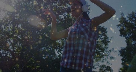 Young Woman Dancing Outdoors with Headphones and Sparkles