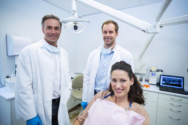 Dentists posing with a smiling female patient at a modern dental clinic. Can be used for promoting dental services, healthcare team profiles, or educational materials about dental care.