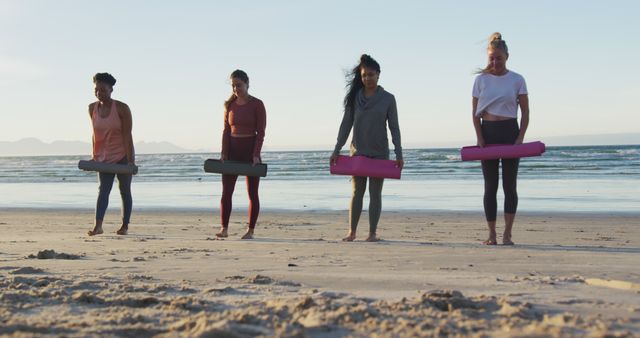 Group of diverse female friends laying out yoga mats at the beach. healthy active lifestyle, outdoor fitness and wellbeing.