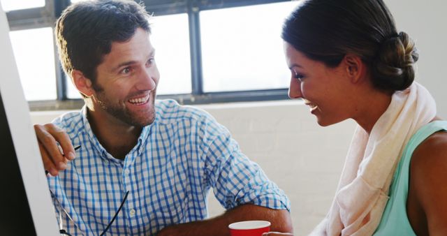 Young professionals engaging in friendly conversation in an office break room. The image can be used to depict workplace communication, teamwork, and a relaxed business environment. Ideal for content related to corporate life, professional interactions, and office culture.