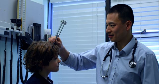 Doctor using medical instrument examining young boy in clinic. Ideal for healthcare, pediatrics, medical examinations, and healthcare professionals depicting patient care scenarios. Suitable for portrayals highlighting routine medical checkups and the doctor-patient relationship.